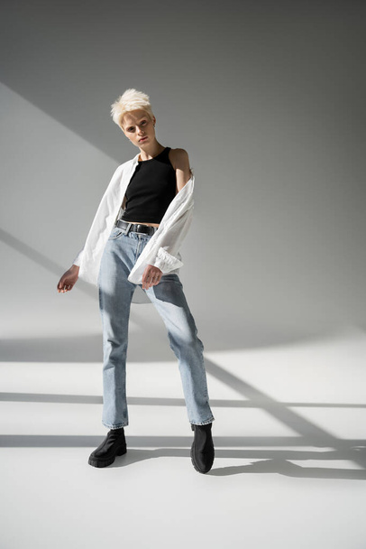 full length of albino woman in black tank top and white shirt posing on grey background with shadows - Φωτογραφία, εικόνα