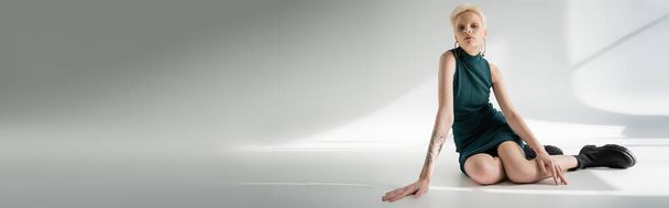 full length of albino woman in tight dress and boots posing on grey background with shadows, banner  - Photo, Image