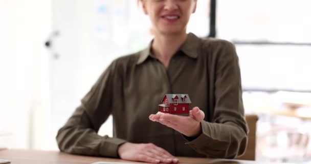 Agentka trzymająca model domu z bliska. Zakup i ubezpieczenie domu i wynajem - Materiał filmowy, wideo