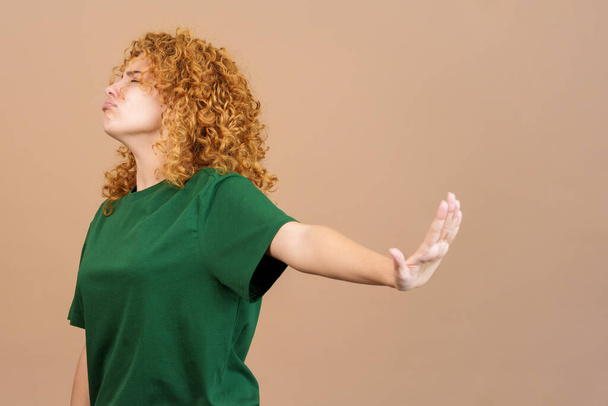 Studio image of a young woman with curly hair and casual clothing gesturing that she wants to know nothing - Photo, Image