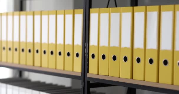 Cartelle gialle con materiali e documenti sono disposti su scaffali. Conservazione della documentazione aziendale e dell'archivio dei servizi - Filmati, video