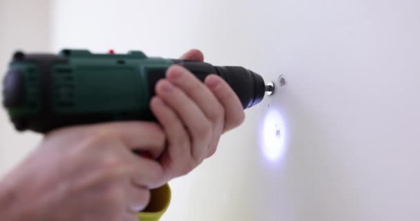 Builder worker making hole in white wall with drill. Modern electric tool for work and repair concept - Footage, Video