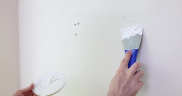 Οικοδόμος ή επισκευαστής με σπάτουλα σοβατεπί λευκό τοίχο closeup. Σχέδιο ανακαίνισης και βελτίωσης σπιτιού - Πλάνα, βίντεο