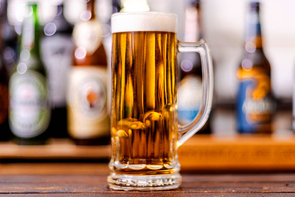 バーを背景にしたフレッシュで冷たいビールのグラス - 写真・画像