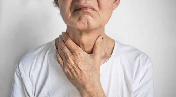 Tightness at the neck of Asian elder man. Concept of sore throat, pharyngitis, laryngitis, esophagitis, thyroiditis, thyrotoxicosis, dysphagia, choking or gasping. - Photo, Image
