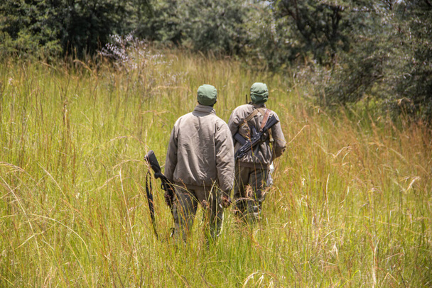Felismerhetetlen Rangerek fegyverrel a zimbabwei állatvédelmi parkban, az Imire Rhino-ban és a Vadvédelmi Területen - Fotó, kép