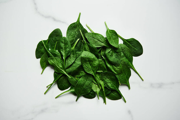 A bunch of Fresh baby spinach leaves on white marble background. High quality photo - Photo, Image