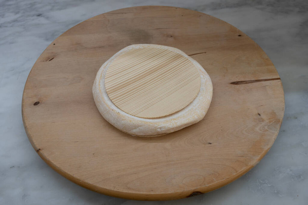 Francouzský kulinářský život. Kousek sýra Reblochon umístěný na dřevěné pánvi - Fotografie, Obrázek