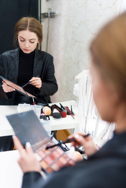 Photo verticale du reflet sur un miroir d'une belle femme se maquillant dans les coulisses - Photo, image