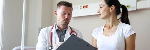 Portrait of female patient at physician appointment at hospital. Physician discussing diagnose with patient and making appointment. Medicine and health care concept - Foto, imagen