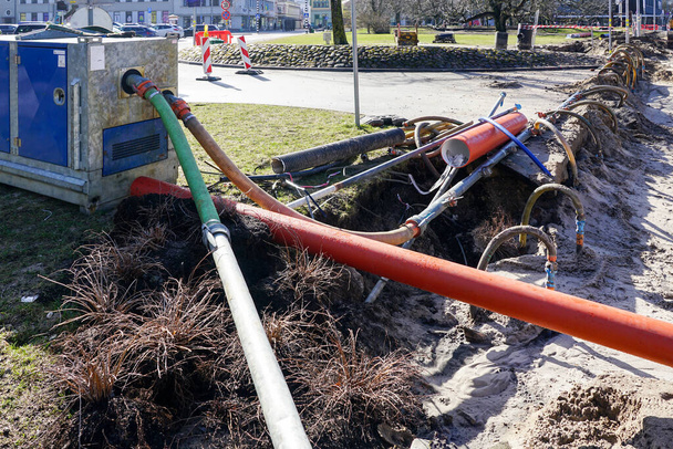 Ontwateringssysteem voor straatreparatiewerkzaamheden met waterpomp, leidingen en slangen, waarschuwingsborden en veiligheidsbanden - Foto, afbeelding