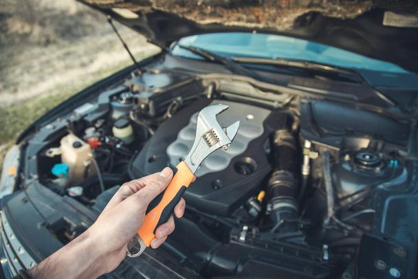 man hand holding car wrench and car in street - Foto, Imagem