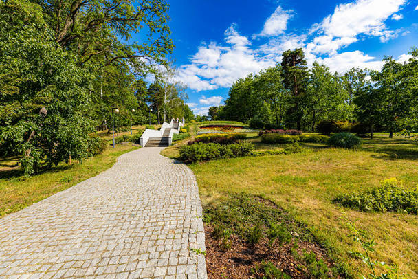 Stalowa Wola, Polen - Juni 2022: Ein schöner, bunter Stadtpark mit einem künstlichen Fluss, einem Brunnen und spazierenden Menschen an einem sonnigen Tag - Foto, Bild