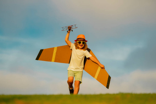 Gyerekjáték. Gyerek fiú kisgyerek játszik játék repülőgép szárny és álmodik jövő. A gyermekjóság és a gyermekkor fogalma. A gyerekek repülővel a mezőn futnak - Fotó, kép