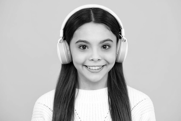 Child music concept. Teenager child girl dances in rhythm of melody, listens song in headphones. Child listening to music through earphones - Foto, imagen