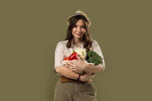Zero waste concept. Young brunette woman holding reusable cotton shopping mesh bag with organic groceries from a market. Concept of no plastic. Zero waste, plastic free. Sustainable lifestyle - Fotografie, Obrázek