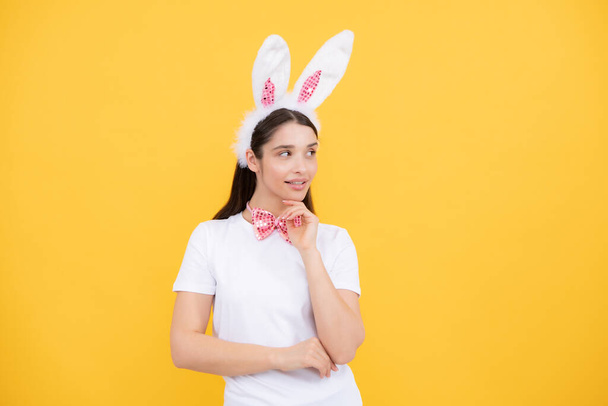 Портрет молодої дівчини з вухами кролика ізольовано на жовтому тлі. Великодній кролик жінка виглядає весело
 - Фото, зображення