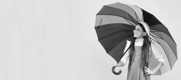 Счастливая девочка-подросток под цветными пумбрами для защиты от дождя в осенний сезон. Ребенок с осенним зонтиком, дождливая погода, горизонтальный плакат, баннер с копировальным пространством - Фото, изображение