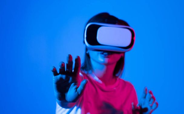 Attractive woman wearing virtual reality goggles. VR headset. Woman using finger to touch on imaginary panel viewing on VR device - Photo, image