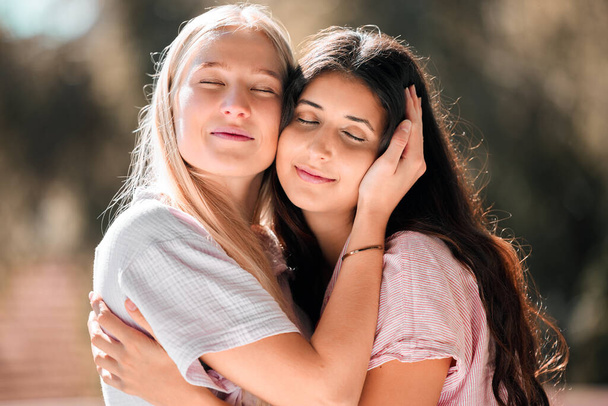 Hug, happy and women with comfort and embrace in nature for bonding, appreciation and support. Smile, caring and friends or gay couple hugging with affection in a garden or park for care and love. - Photo, Image