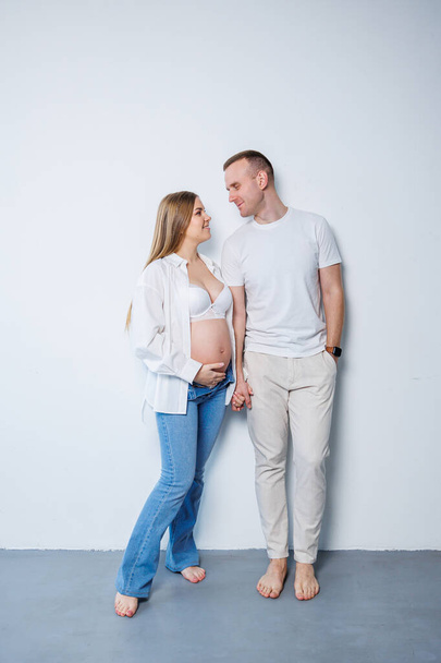 Happy married couple man and pregnant woman on white background in studio a pregnant woman and her husband. A married couple in love - Fotoğraf, Görsel