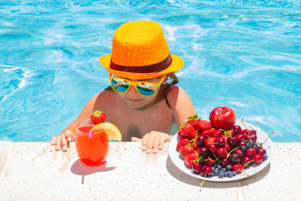 Criança feliz brincando na piscina. Férias de verão. Fruta de verão para crianças. Menino relaxante em uma piscina se divertindo durante as férias de verão - Foto, Imagem