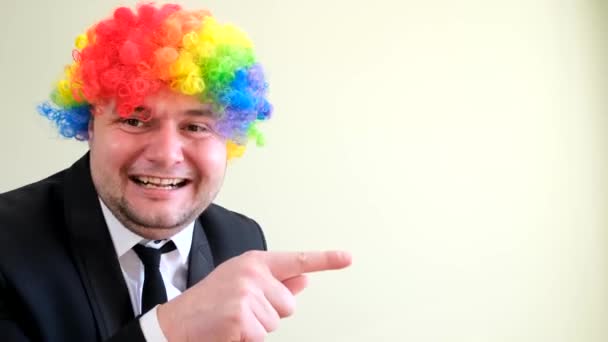 Portrét bláznivého šťastného muže v obleku a masce s obarvenými vlasy pózující na bílém pozadí. Natáčení veselého podnikatele ve studiu. - Záběry, video