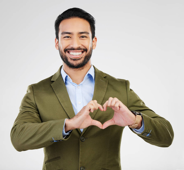 Portrait, heart and hand gesture with a business man in studio on a gray background for health or love. Hands, emoji and shape with a happy male employee showing a symbol or sign of affection. - Photo, Image