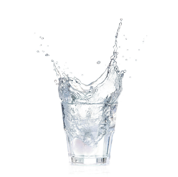 παγάκια, εκτοξευμένο σε ποτήρι νερό, που απομονώνονται σε λευκό - Φωτογραφία, εικόνα