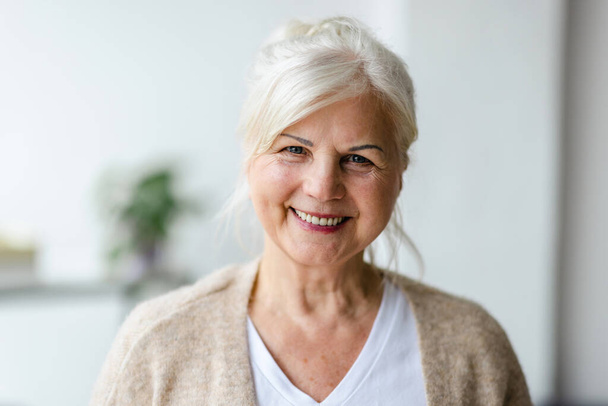 Portrét usměvavá starší ženy při pohledu na fotoaparát - Fotografie, Obrázek