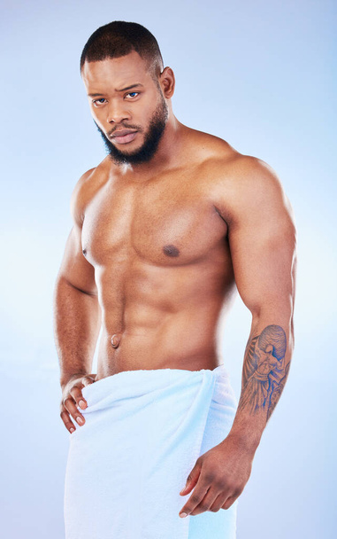 Portrait, skincare and body with a man on white background and wearing a towel in studio after cleaning. Hygiene, grooming and serious muscular african male model posing shirtless in his bathroom. - Фото, изображение