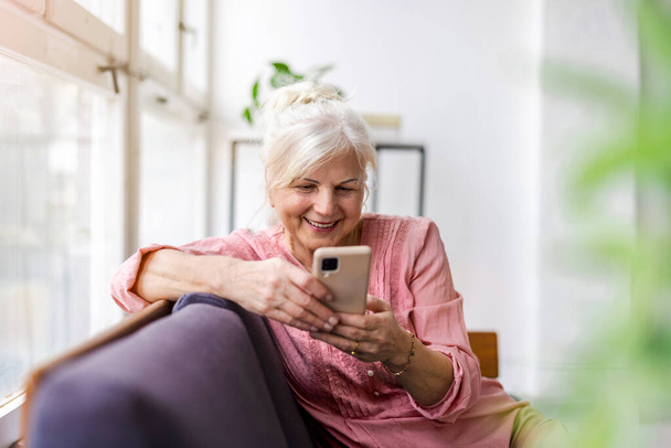 Smiling senior woman using smartphone  - Fotó, kép