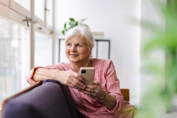 Smiling senior woman using smartphone  - Zdjęcie, obraz