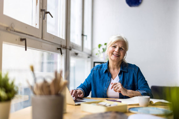 Portrait of smiling mature businesswoman working in an office  - Фото, изображение
