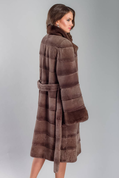 A beautiful young woman of European complexion wearing a fur coat, studio photoshoot - Photo, Image