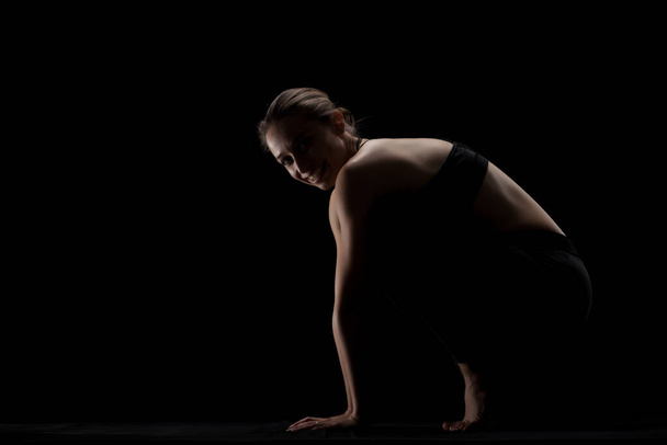 cute caucasian girl exercising yoga poses against dark backgroung. side lit silhouette. - Фото, изображение