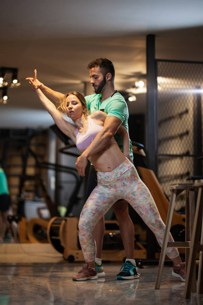 Couple in love dancing bachata and tango. Boy and girl having fun during exercise break in a fitness studio. - 写真・画像