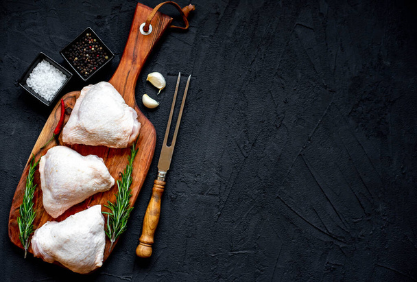 raw chicken thighs on black stone background with copy space for your text - Photo, Image