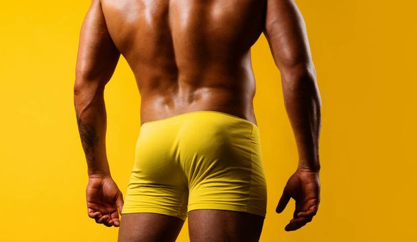 Man buttocks in yellow underpants. Muscular man with muscular buttocks. Bare nude torso, Naked male ass - 写真・画像