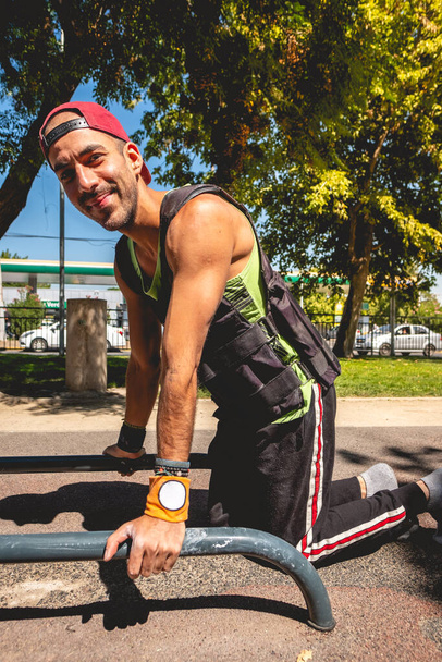 Sunny street cvičení: šťastný latinsky mužský atlet cvičení na paralelních barech v městském parku - Fotografie, Obrázek