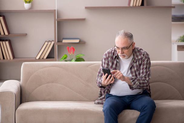 Старий розмовляє по телефону вдома під час пандемії
 - Фото, зображення