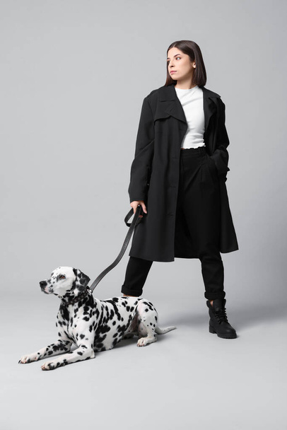 Beautiful young woman with her adorable Dalmatian dog on light grey background. Lovely pet - Foto, afbeelding