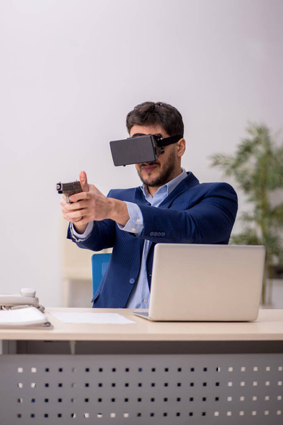 Joven empleado disfrutando de gafas virtuales en el lugar de trabajo - Foto, imagen