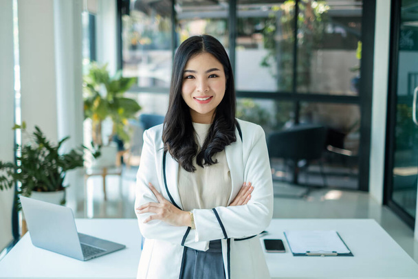 Азиатская женщина-предприниматель с деловым успехом стоит счастливо улыбаясь в офисе. - Фото, изображение