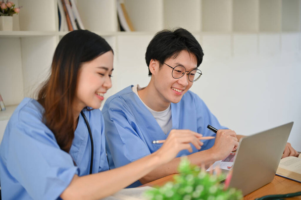 Due giovani studenti di medicina intelligenti e felici stanno studiando e facendo un progetto medico in biblioteca insieme. - Foto, immagini