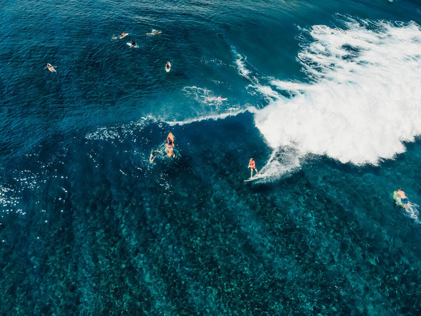 Aerial view with surfing on wave. Perfect waves with surfers in tropical ocean - 写真・画像