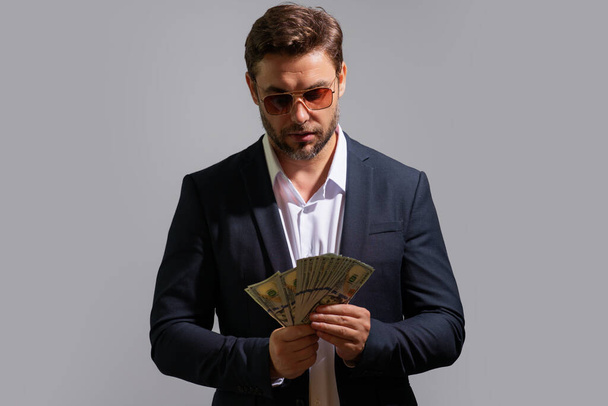 Good payment. Handsome man holding money isolated over grey studio. Money in dollar banknotes. Pile of cash, finance, investment and money saving. Mockup banner - Foto, imagen