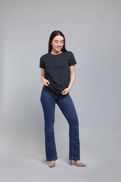 Young woman in stylish jeans on grey background - Fotografie, Obrázek