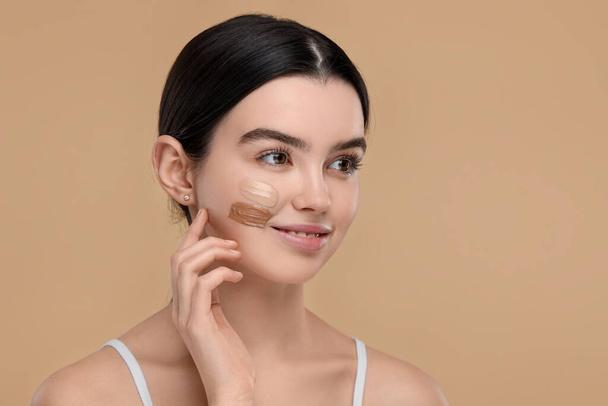 Teenage girl with swatches of foundation on face against beige background. Space for text - Fotografie, Obrázek