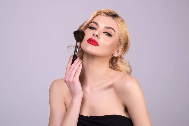 Beautiful woman applying make-up powder on the cheek. Cosmetic powder brush. Perfect skin and natural makeup - Фото, зображення